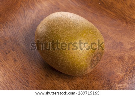 A gold kiwi on the wood dish(tray, bowl) isolated white reflected at the studio.