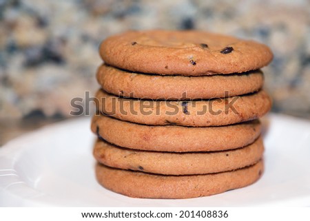 Freshly baked chocolate chip cookies stacked in a pile on a paper plate