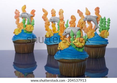 Aquatic under the sea themed cup cakes created at home with royal icing coral and sea weed marshmallow fondant dolphins and fish. Perfect for summer parties