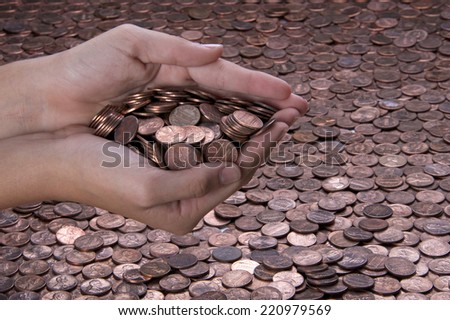 young hands cupped together holding pennies over a background of pennies