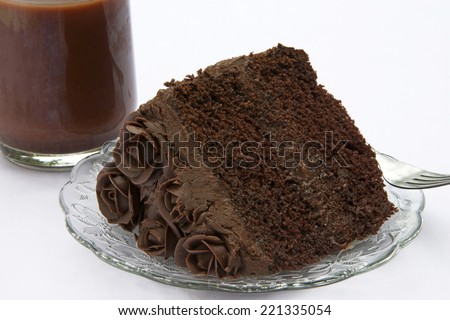 A slice of Triple Chocolate cake with chocolate cream filling topped with handmade chocolate frosting roses on white table cloth