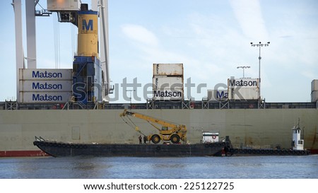 OAKLAND, CA - OCTOBER 21, 2014: Marine Express ship transporting a tractor past Matson Cargo Ship docked at the Port of Oakland. Marine Express provides commercial and government fleet services.