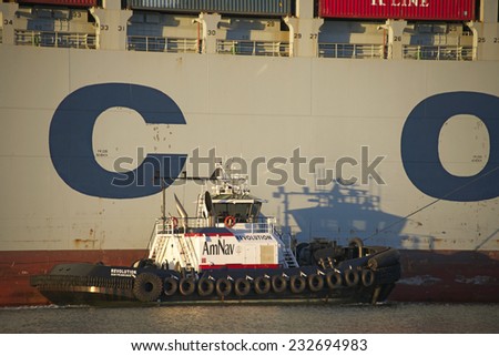OAKLAND, CA - NOVEMBER 23, 2014: American Navigation (AmNav) Tugboat REVOLUTION off the Starboard side of COSCO KAOHSIUNG Cargo Ship to escort the cargo ship out of the Port of Oakland.