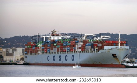 OAKLAND, CA - NOVEMBER 23, 2014: Tugboats move vessels that should not move themselves, such as ships in a crowded harbor. Multiple Tugboats escort COSCO KAOHSIUNG Cargo Ship from the Port of Oakland.