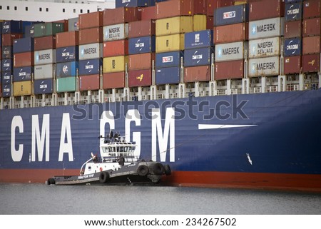 OAKLAND, CA - NOVEMBER 29, 2014: Tugboat Z-FOUR at the Starboard Bow of the Container ship CMA CGM NORMA. Tugboats move vessels that should not move themselves, such as ships in a crowded harbor.