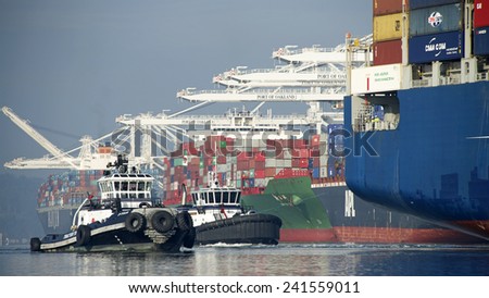 OAKLAND, CA - JANUARY 04, 2014: Tugboats move vessels that should not move themselves, such as ships in a crowded harbor.Tugboats Z-FOUR and AHBRA FRANCO at the Stern of Cargo Ship CMA CGM CENTAURUS.