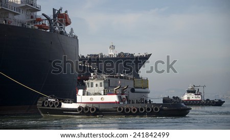 ALAMEDA, CA - JANUARY 05, 2014: AmNav Tugboat REVOLUTION pulling from the Bow of U.S. Naval Ship MONTFORD POINT to assist the ship from the dock at the Alameda Point.