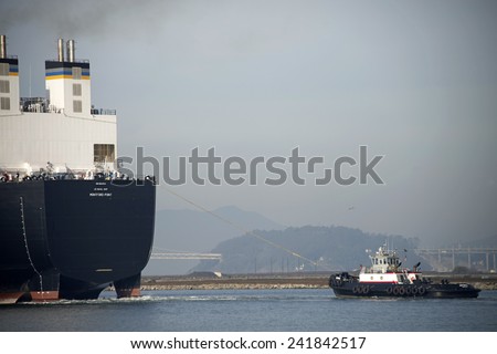 ALAMEDA, CA - JANUARY 05, 2014: Tugboat ASTORIA pulling from the stern of U.S. Naval Ship MONTFORD POINT to assist the ship from the dock at the Alameda Point, previously Naval Air Station Alameda.