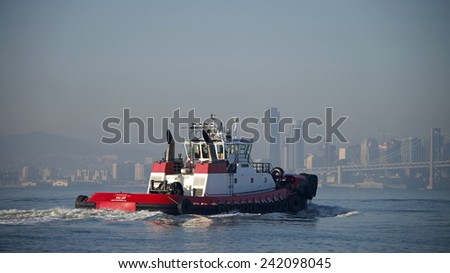 OAKLAND, CA - JANUARY 06, 2015: Tugs move vessels that should not move themselves, such as ships in a crowded harbor. Tugboat VALOR departing the inner Harbor at the Port of Oakland on a hazy day.