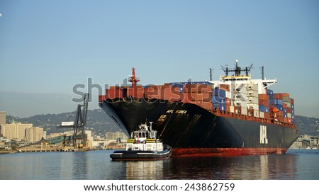 OAKLAND, CA - JANUARY 12, 2015: American President Lines Ltd. (APL) Cargo Ship KOREA entering the Port of Oakland with Tugboat DELTA BILLIE pulling from the bow of the ship.