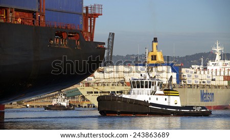 OAKLAND, CA - JANUARY 12, 2015: APL Cargo Ship KOREA passing Matson Cargo Ship MANOA while both ships enter the Port of Oakland. Tugboats efficiently assist the giant ships through the port safely.