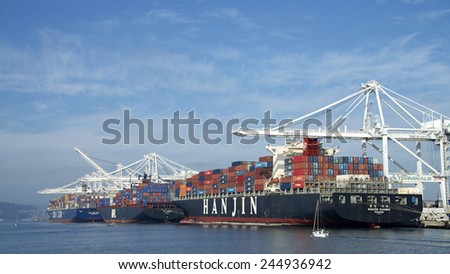 OAKLAND, CA - JANUARY 17, 2015: The Port of Oakland's cargo volume makes it the fifth busiest container port in the United States. Many recreational boaters sail by the giant ships in port.