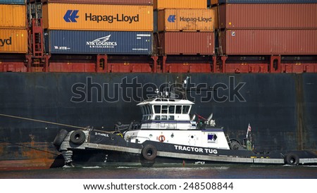 OAKLAND, CA - JANUARY 30, 2015: Tugs move vessels that should not move themselves, such as ships in a crowded harbor. Tugboat Z-THREE assists Cargo Ship BOSTON EXPRESS to enter the Port of Oakland.
