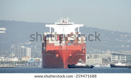 OAKLAND, CA - MARCH 09, 2015: Hamburg SUD Cargo Ship SANTA BARBARA entering the Port of Oakland. Tugboats work in tandem to turn the ship prior to docking in the Middle Harbor.