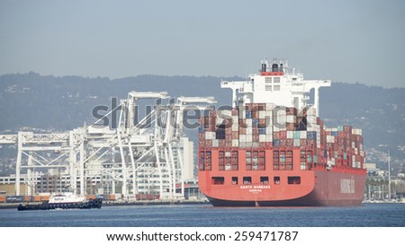 OAKLAND, CA - MARCH 09, 2015:  Hamburg SUD Cargo Ship SANTA BARBARA entering the Port of Oakland. Tugboats work in tandem to turn the ship prior to docking in the Middle Harbor.