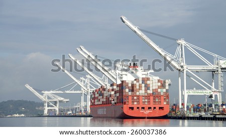 OAKLAND, CA - MARCH 11, 2015: Hamburg SUD Cargo Ship SANTA BARBARA docked at the Port of Oakland. Loading completed, the ship waits for tugboat assistance to depart the port.