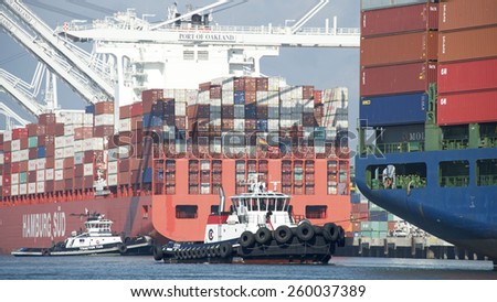 OAKLAND, CA - MARCH 11, 2015: Tugboat VETERAN assisting Cargo Ship HYUNDAI SUPREME into the Port of Oakland as Tugboat Z-THREE begins assisting Cargo Ship SANTA BARBARA with departure from the port.