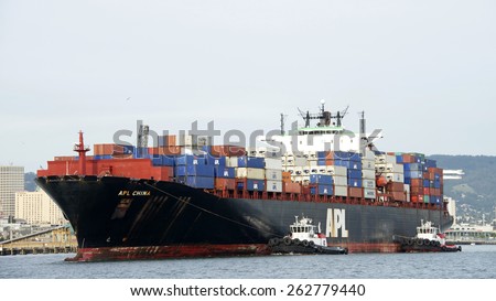 OAKLAND, CA - MARCH 21, 2015:  APL Cargo Ship CHINA entering the port of Oakland with Tugboats VETERAN and VALOR assisting. Tugboats are vital for safe, efficient entry and exit for the large ships.