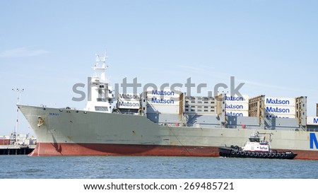 OAKLAND, CA - APRIL 13, 2015: PATRICIA ANN on the Port side of Matson Cargo Ship MAUI assisting the vessel maneuver into the Port of Oakland. A tugboat maneuvers vessels by pushing or towing them.