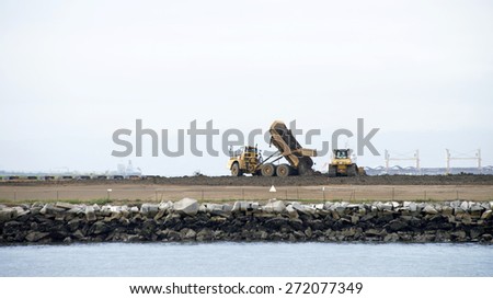ALAMEDA, CA - APRIL 22, 2015: Clean up continues on the prior Navy Industrial Waste Dump located on the North West Corner of Alameda Point. Tractors can be seen dumping and spreading new dirt.