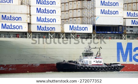 OAKLAND, CA - APRIL 22, 2015: Tugboat PATRICIA ANN on the Port side of Matson Cargo Ship MOKIHANA, assisting the vessel to maneuver into the Port of Oakland.