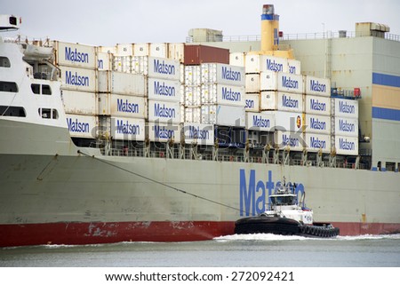 OAKLAND, CA - APRIL 22, 2015: Tugboat PATRICIA ANN on the port side of Matson Cargo Ship MOKIHANA, assisting the vessel to maneuver to the Port of Oakland.