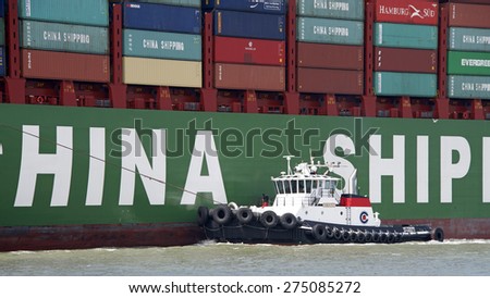 OAKLAND, CA - MAY 03, 2015: Tugboat VETERAN off the port side of CSCL SPRING, assisting the vessel to maneuver into the Port of Oakland.  A tugboat maneuvers vessels by pushing or towing them.