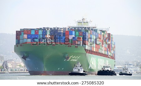 OAKLAND, CA - MAY 03, 2015: China Shipping Lines Cargo Ship CSCL SPRING entering the Port of Oakland with multiple tugboats assisting the vessel to maneuver.