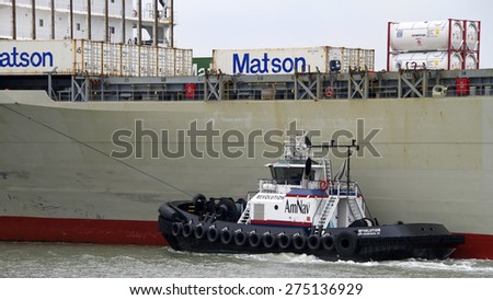 OAKLAND, CA - MAY 04, 2015: Tugboat REVOLUTION on the port side of Cargo Ship MANOA, assisting the vessel to maneuver into the Port of Oakland.