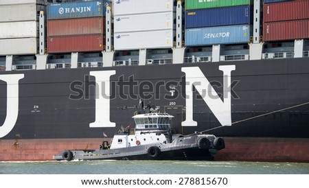 OAKLAND, CA - MAY 13, 2015: Tugboat Z-FIVE off the Starboard side of Cargo Ship HANJIN BUDDAH, assisting the vessel to maneuver into the Port of Oakland.