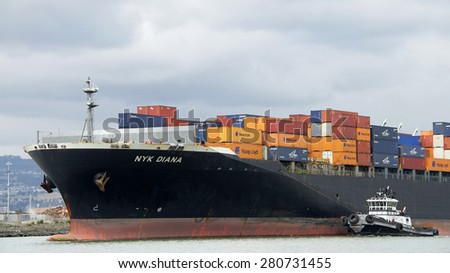 OAKLAND, CA - MAY 14, 2015: Tugboat Z-THREE off the Port side of APL DIANA, assisting the vessel to maneuver out of the Port of Oakland. A tugboat maneuvers vessels by pushing or towing them.