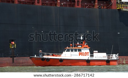 OAKLAND, CA - JUNE 04, 2015: Pilot vessel GOLDEN GATE approaches APL Cargo Ship DUBLIN to pick up the harbor pilot as the vessel departs the Port of Oakland. The pilot must jump from the moving ship.