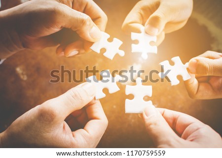 Hand of diverse people connecting jigsaw puzzle. Concept of partnership and teamwork in business