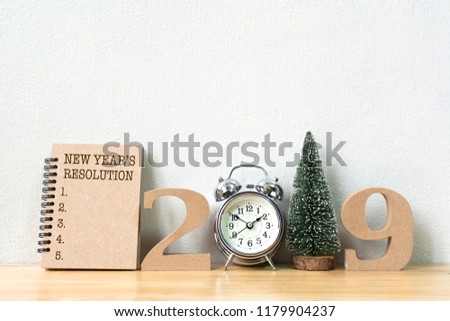 New year\'s resolution on notebook and wood number 2019 with clock and christmas tree on wood table and copy space