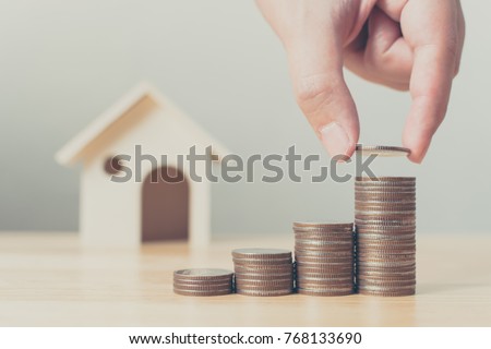 Property investment and house mortgage financial concept, Hand putting money coin stack with wooden house