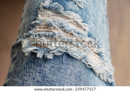 Closeup of tear in old worn out jeans in vintage tone