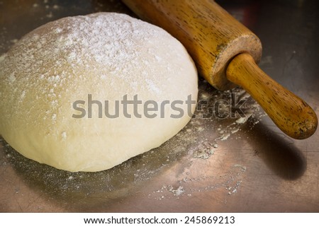 Classic wooden rolling pin with freshly prepared dough and dusting of flour