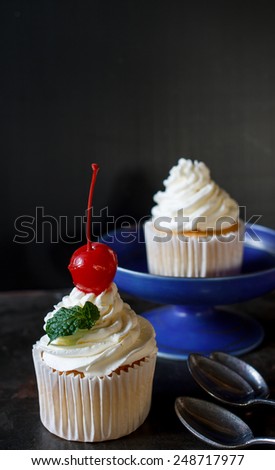vanilla sweet cupcake with italian butter cream serve on blue plate , image dark tone