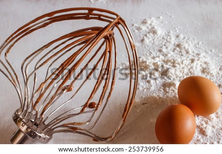 whisk machine with organic eggs and flour put on vintage white table