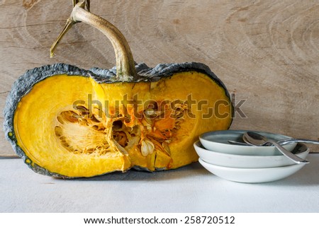 Pumpkin cut open with seeds and china small plate put on old wood, still life image