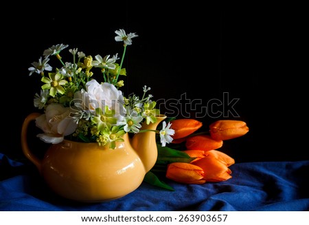 Flower in a yellow tea pot and orange tulip,cozy home rustic decor, cottage living, still life image dark tone