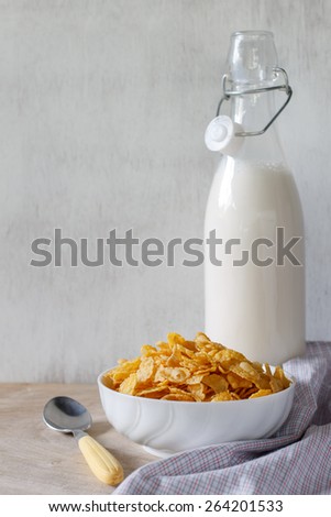 cornflakes served in white cup with fresh milk put on vintage white wood