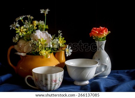 Flower in a yellow tea pot and vintage cup of coffee,cozy home rustic decor, cottage living, still life image dark tone
