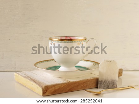 Vintage cup coffee with tea bag on woodden board with flower, image soft tone and soft focus.