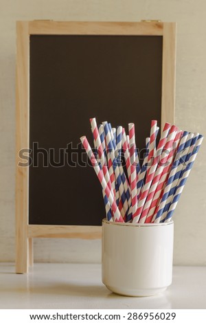 Blue and pink straws paper in white cup. Image soft focus and soft tone.