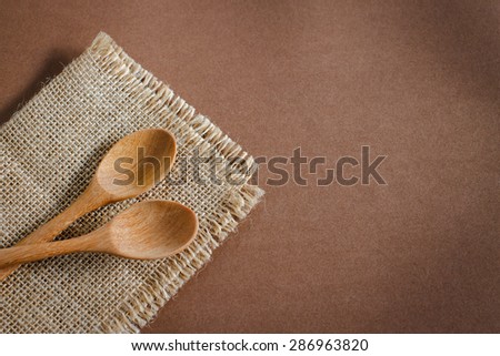 Serving spoons on burlap cloth on wooden surface. Image brown tone.