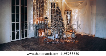panoramic photo warm, cozy evening in Christmas room interior design,Xmas tree decorated by lights presents gifts toys, candles, lanterns, garland lighting indoors fireplace.holiday living room.New