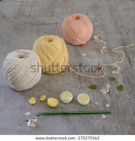 Ball of cream yarn with crochet hook or needle sticking through