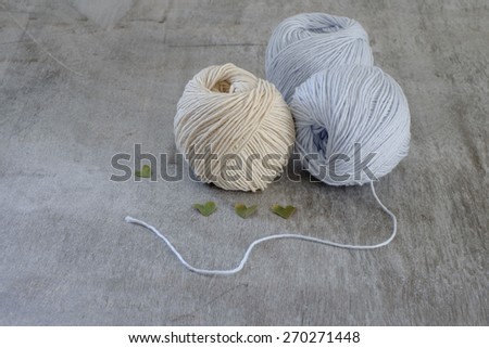 Ball of cream yarn with crochet hook or needle sticking through