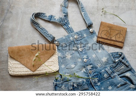 Outfit of casual woman. Denim overall with a summer female leathern bag on a wooden background